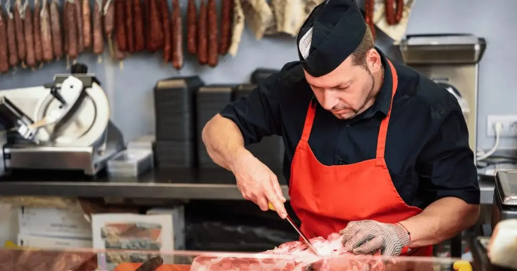 Carnicero en Carnicería cortando filetes, y EL REAL DECRETO 1021/2022 Y SU IMPORTANCIA PARA LA HOSTELERÍA