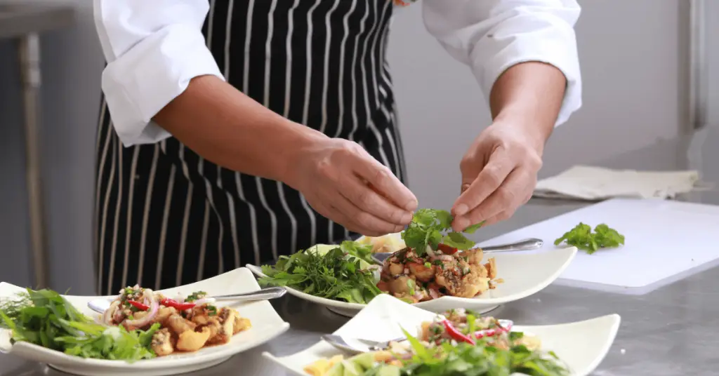 Cocinero decorando platos y la importancia del real decreto 1021/2022